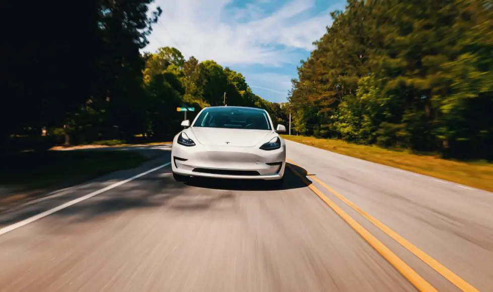 A new Tesla Model 3 all electric vehicle driving down a country road
