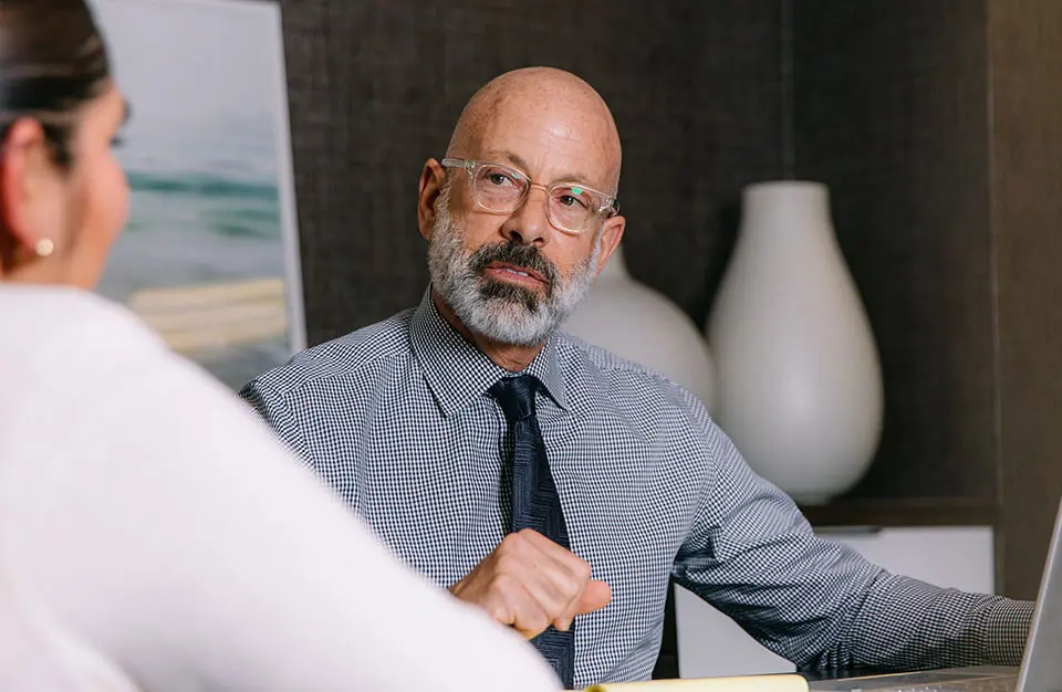 Sophisticated attorney in glasses and gray beard talking to a client