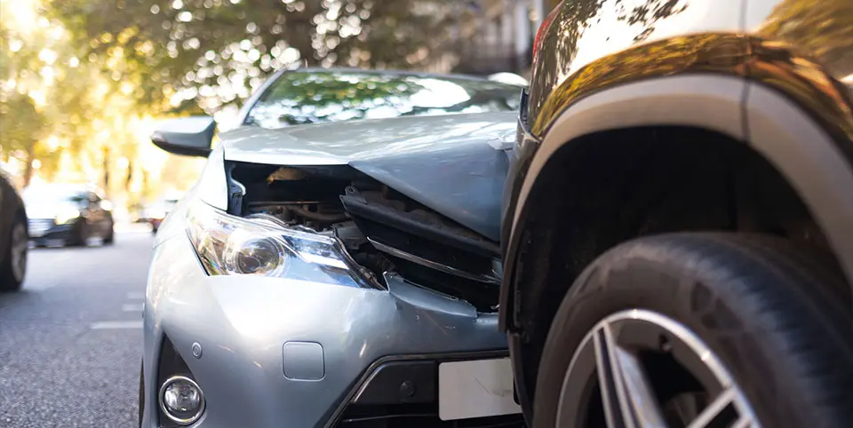 Car Accident - rear-end: gray car rammed into an SUV on a leafy street